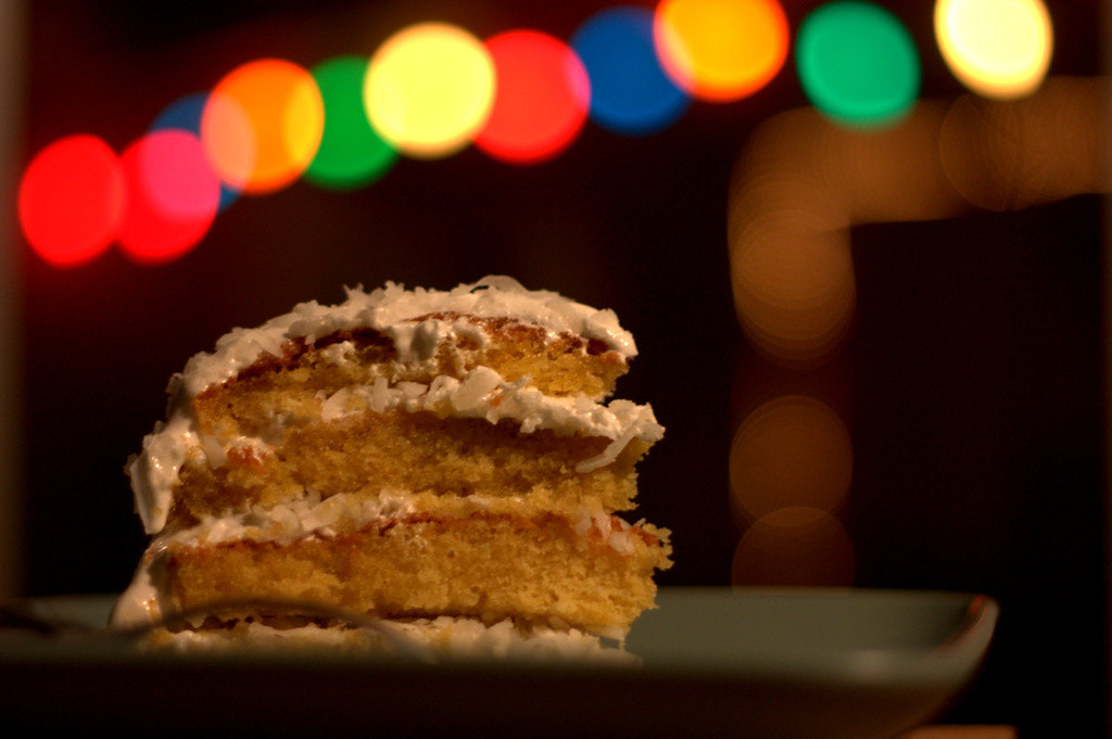 Slice of coconut cake with Christmas lights in background